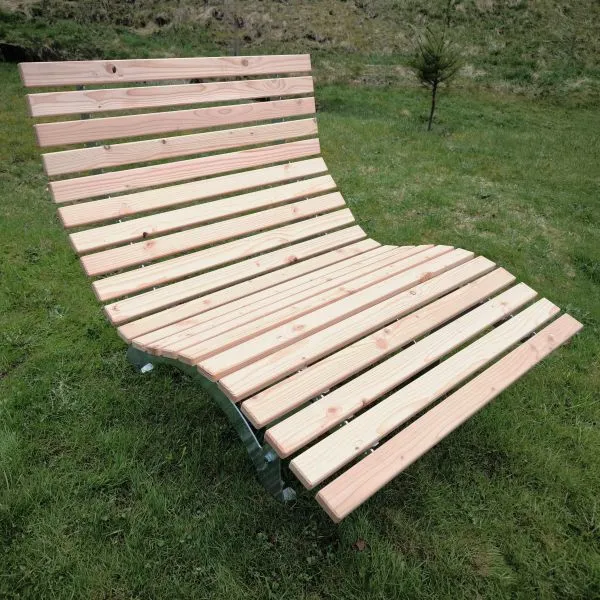 Ergonomisches Waldsofa / Wellenliege in 120 cm Breite mit feuerverzinktem Stahlgestell und natürlichen Holzlatten aus Douglasie auf einer grünen Wiese.